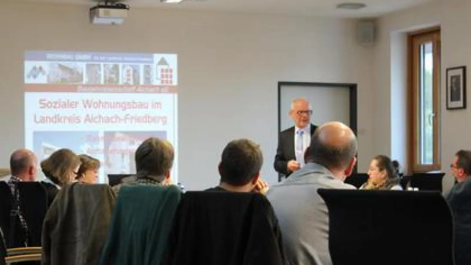 Max Rössle   (stehend), Geschäftsführer der Wohnbau GmbH, erklärte dem Aindlinger Gemeinderat am Dienstagabend anhand einer Powerpoint-Präsentation wie man beim Thema sozialer Wohnungsbau zusammenarbeiten könnte.