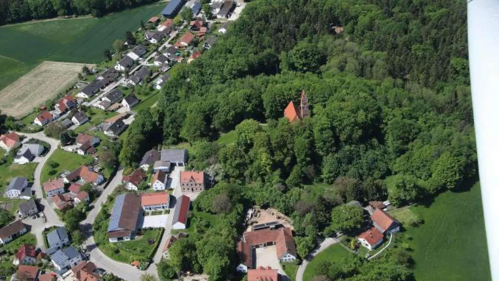 Idyllisch im Wald   steht die Oberwittelsbacher Burgkirche. Mit dem Ende der Sanierung dürfte die Zahl der Touristen, die den Stammsitz der Wittelsbacher besuchen, weiter steigen. Oben am Bildrand ist das neue Naturhotel Wittelsbach zu sehen.