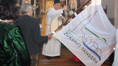 <b>Pfarrer Michael Heinrich</b> weihte die neue Fahne des Vereins „Zukunft Tandern” mit dem Logo des Vereins ein. (Foto: Franz Hofner)