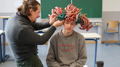 <b>Simon Wiese vom Staatstheater</b> Augsburg zeigte den Schülern, wie man den Kopf und die Haare für das Tragen einer Perücke vorbereitet und verwandelte Paul Hermann in das Paulinchen. (Foto: Alice Lauria)