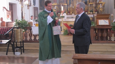 <b>Pfarrer Tobias Seyfried</b> überreichte Karl Agatsy die Urkunde mit Ehren und ein Geburtstagsgeschenk. (Foto: Katharina Wachinger)