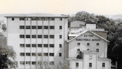 <b>Im Jahr 1955</b> wurde das heute noch bestehende sieben Stockwerke hohe Mühlengebäude (links) erbaut. Die alte Mühle (rechts) aus dem Jahr 1861 wurde 1964 abgebrochen.  (Foto: Aktienkunstmühle Aichach)