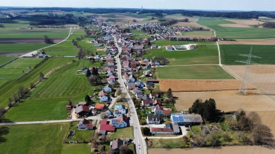 Hollenbach ist ein kilometerlanges Straßendorf. Im Krebsbachtal zieht es sich von Motzenhofen bis Igenhausen. Im Hintergrund zu sehen ist der Schönbacher Fernsehturm, links das Sportgelände des TSV. Die Aufnahme stammt von Bürgermeister Xaver Ziegler, einem begeisterten Drohnenfotografen.