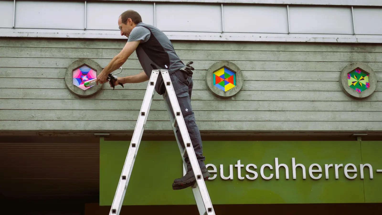 <b>Hausmeister Jochen Hoffmann</b> befestigte die lackierten Schicht-leimplatten in den Aussparungen der Sichtbetonfassade (Foto: Michael Lang)