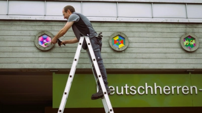 <b>Hausmeister Jochen Hoffmann</b> befestigte die lackierten Schicht-leimplatten in den Aussparungen der Sichtbetonfassade (Foto: Michael Lang)