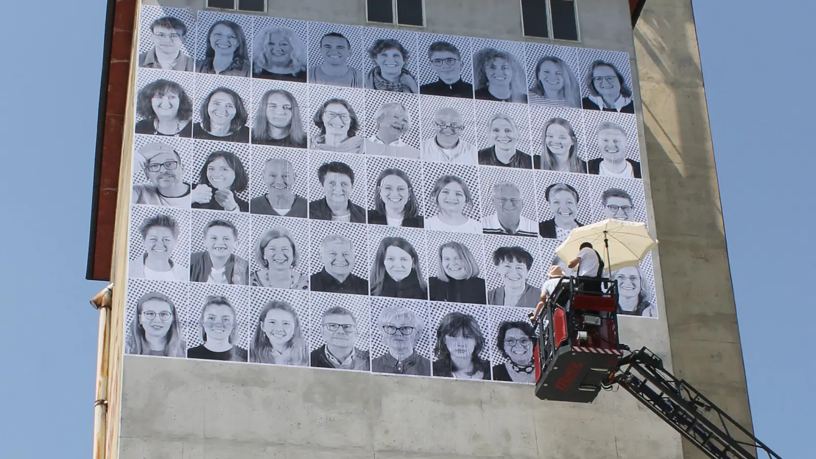 150 Portraits von Menschen aus der Region wurden auf den Turm von Landhandel Reitberger an der Donauwörther Straße in Aichach tapeziert. Weitere knapp 40 der 1,5 Meter hohen Portraits sind ab Freitag am San-Depot und am Tandlmarkt zu sehen. (Foto: Wolfgang Glas)