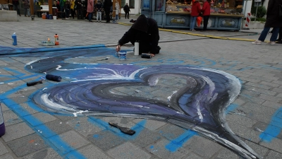 „Die Bunten“, ein legaler Graffiti-Verein aus Augsburg, nutzten den Tandlmarkt für ihre Straßenkreidekunst. Auf unserem Bild ist Nico Büchner beim zeichnen zu sehen. (Foto: Nayra Weber)